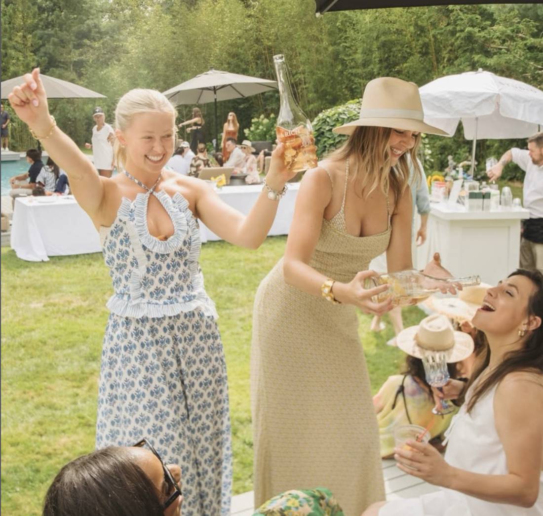 Friends pouring A Rich Rosé at a garden party by the pool